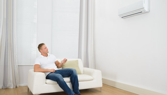 Man Adjusting The Temperature Of Air Conditioner
